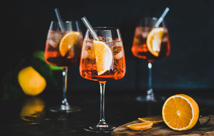 Aperol Spritz mit Orangenscheiben und Strohhalm auf dunklem Hintergrund – stimmungsvolle Cocktail-Inszenierung