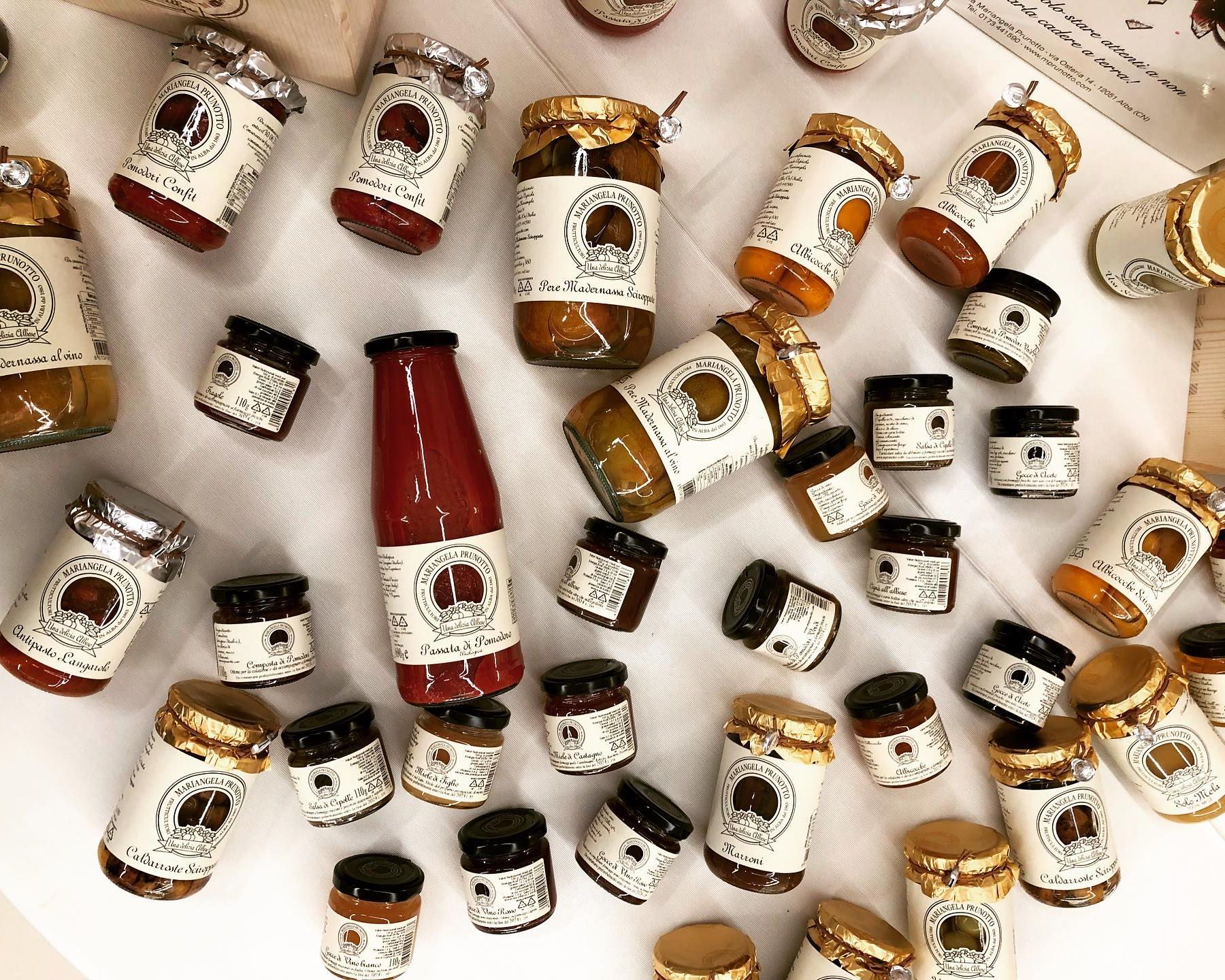 Zahlreiche Gläser und Flaschen mit Mariangela Prunotto Feinkostprodukten auf weissem Untergrund ausgelegt.