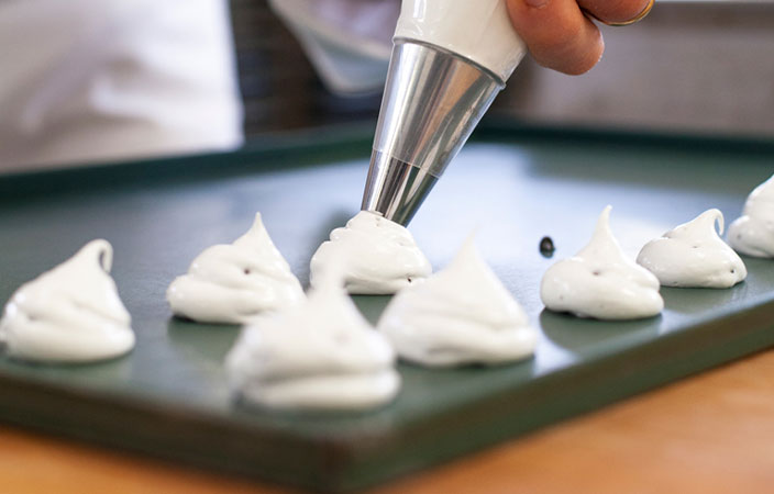 Herstellung von Meringue – italienisches Baiser Gebäck wird aufgespritzt