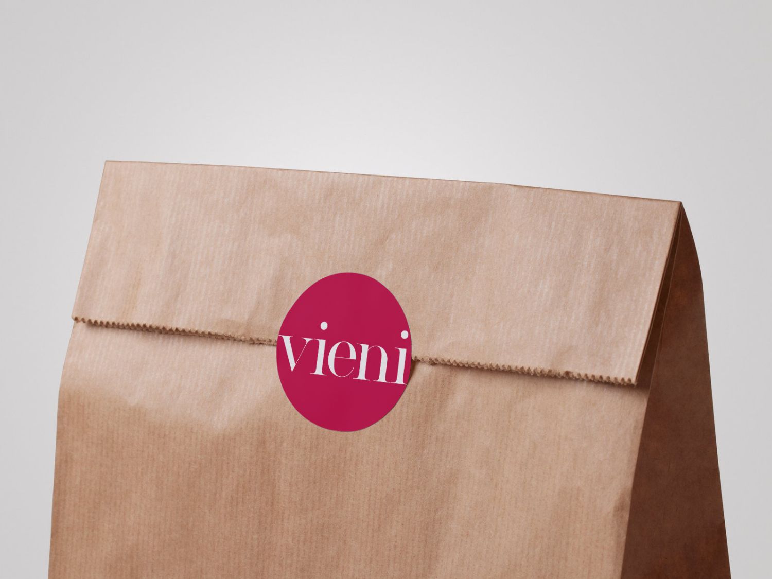 Braune Papiertuete mit magenta Sticker und weissem 'vieni' Logo. Die Tuete ist oben gefaltet und gezackt.