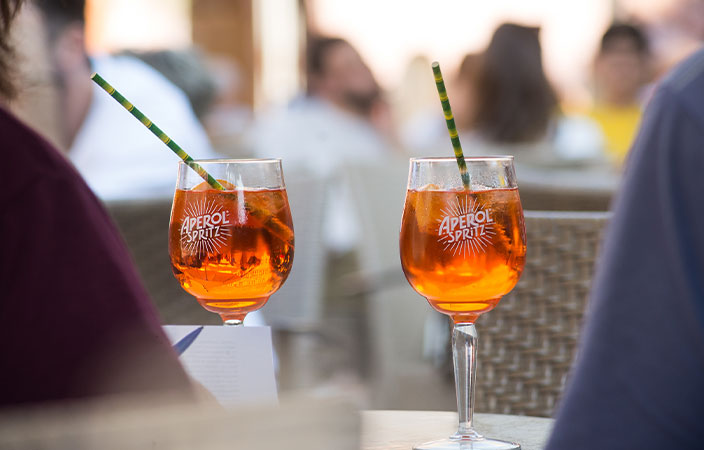 Zwei Aperol Spritz mit Strohhalm auf einem Aussenrestaurant-Tisch – sommerlicher Aperitivo im Freien