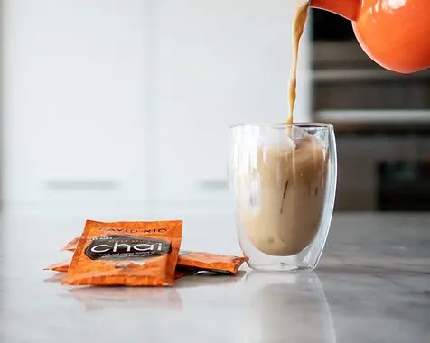 David Rio Chai Latte wird in ein Doppelwandglas eingegossen – cremiges Heissgetränk mit orangefarbener Verpackung