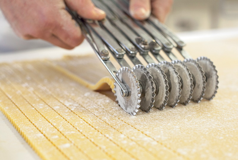 Teig wird geschnitten für italienisches Gebäck – handwerkliche Herstellung von Süsswaren