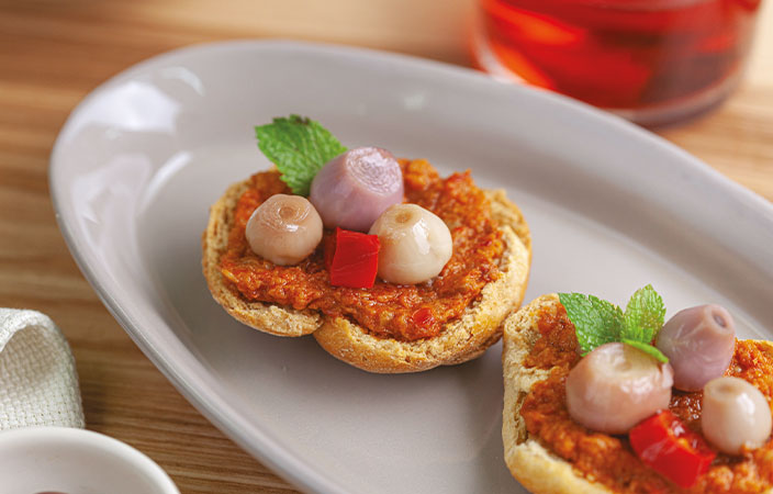 Contadini Friselle mit Tomatencreme, Perlzwiebeln und frischer Minze auf weissem Teller – apulische Spezialität